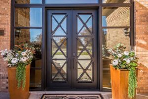 Geometric wrought iron double doors with large and simplistic custom windows surround the double doors.